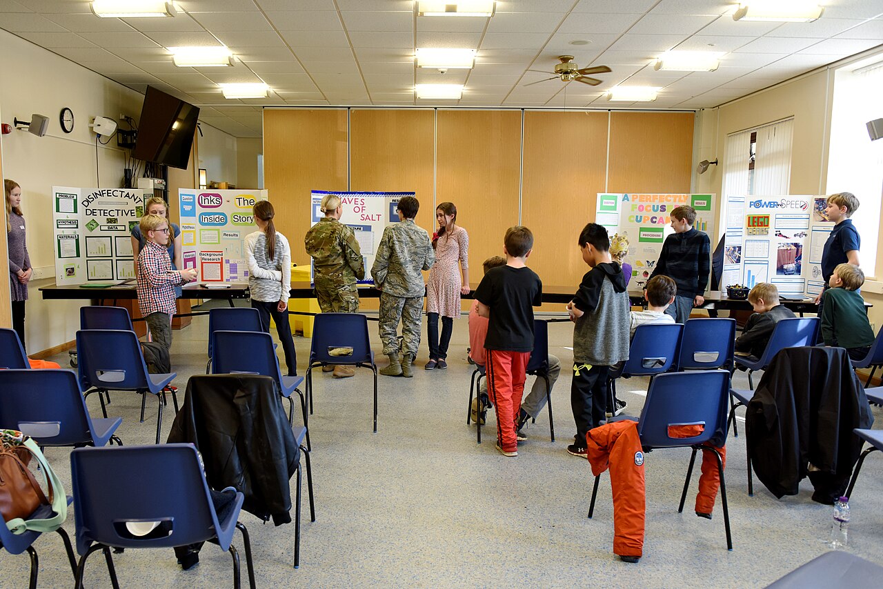 Students presenting classic tri-fold poster boards at a school science fair